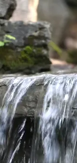 Serene waterfall flowing over moss-covered rocks in nature.