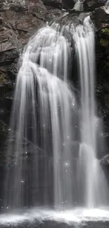 Tranquil waterfall cascading down rocky cliffs surrounded by lush greenery.