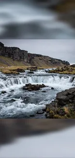 Serene waterfall flowing through rocky landscape under a cloudy sky.