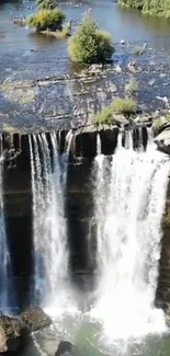 Cascading waterfall with lush greenery and rocks in a serene landscape.