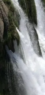 Waterfall cascading down rocky terrain with lush greenery.