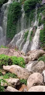 Serene waterfall cascades amidst lush green scenery with rocks.