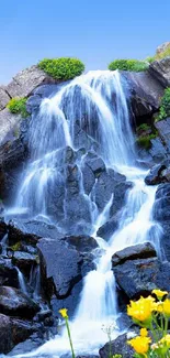 Serene waterfall cascading over rocks with vibrant greenery and blue sky.