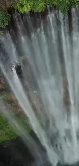 Waterfall with lush green foliage on a mobile wallpaper background.