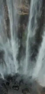 Cascading waterfall with mist and rocks.