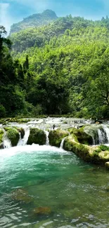 Serene waterfall with lush green mountains and clear blue sky.