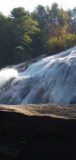 Waterfall cascading down a rocky slope surrounded by lush forest.