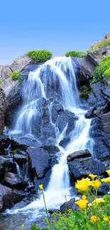 Serene waterfall and wildflowers under a clear blue sky.