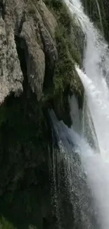 Mobile wallpaper of a serene waterfall with rocky surroundings.