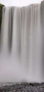 Cascading waterfall with gray mist and rocks in a serene natural setting.