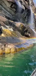 Waterfall with rainbow over serene green water.