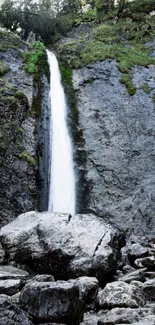 Waterfall cascading over rocks in a serene mountain setting.