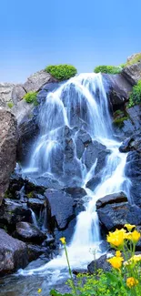 Cascading waterfall amidst lush greenery with a clear blue sky.