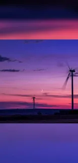 Scenic sunset with wind turbines in tranquil purple hues.