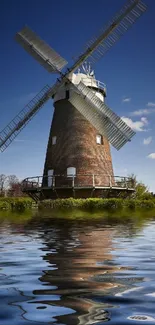 Windmill reflected in water with blue sky.