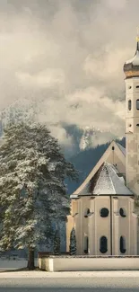 Serene snow-covered church with mountain backdrop in winter.