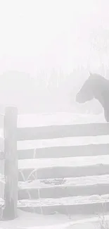 Horse behind a wooden fence in a snowy, misty landscape.