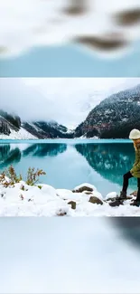 Woman sitting by a snowy turquoise lake with mountains in winter.