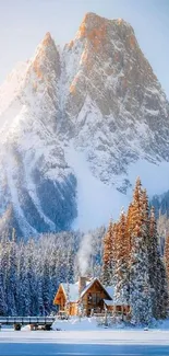 Snowy mountain with cabin and trees under a blue sky.