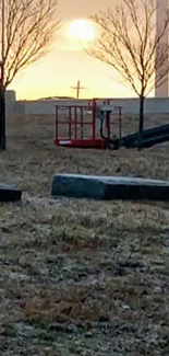 Serene sunset scene at a memorial field with trees and orange sky.