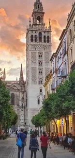 Historic tower at sunset with people walking in a vibrant city street.