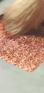 Close-up of a rose gold glitter texture with a makeup brush stroke.