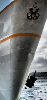 Gray ship under cloudy sky with ocean backdrop.