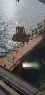 A ship's deck with suspended cargo over the blue ocean.