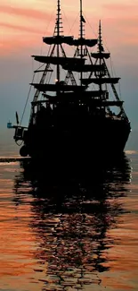 Silhouette of a ship on calm waters at sunset.