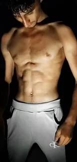 Shirtless man with defined abs in dark background.