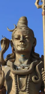 Bronze statue of Lord Shiva with a trishul against a blue sky.