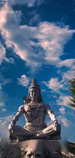 Shiva statue against a vibrant blue cloudy sky, exuding peace and serenity.