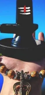 Hand holding Shivling with blue background.