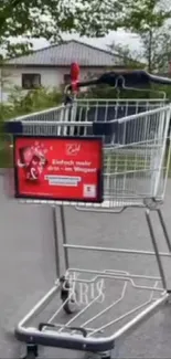 Shopping cart on suburban street with greenery in background.