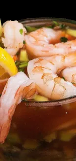 Vibrant shrimp cocktail in a glass with lemon slice on black background.