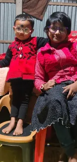 Two siblings wearing glasses indoors with stylish red and black outfits.