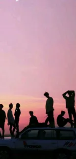 Silhouette of people on a car at sunset with a pink pastel sky.