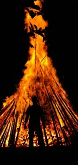 Silhouette standing before a large bonfire glowing brightly.