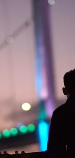 Silhouette of a person against vibrant, blurred city lights at night.