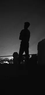 Silhouette of a person against a night sky on a rooftop.