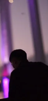 Silhouette in front of purple city lights during the night.