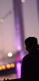 Silhouette of a person against purple city lights in the evening.