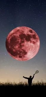 Silhouette of person with racquet and red moon in starry night sky.