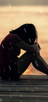 Silhouette of a person sitting on a pier at sunset by a tranquil lake.