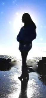 Silhouette of person on reflective beach with blue sky background.