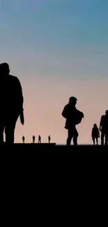 Silhouetted figures during a beach sunset create a captivating mobile wallpaper.