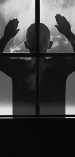 Silhouette of a person behind a foggy window in black and white.