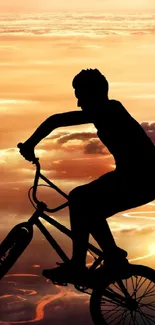 Silhouette of BMX biker against a vibrant sunset sky and clouds.