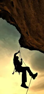 Silhouette of a climber scaling a cliff against a sunset sky.