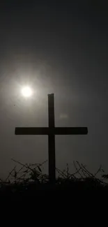 Silhouette of a cross with sunlight creating a halo effect behind it.